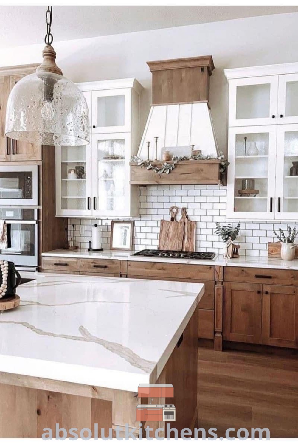 A kitchen with wooden cabinets and white marble countertops, showcasing a central island, epitomizing modern farmhouse barndominium interior design. This beautiful kitchens farmhouse setting offers cozy aesthetic and decorating ideas for new house kitchens, providing inspiring design tips for homeowners. Discover more about these design trends at absolutkitchens.com.