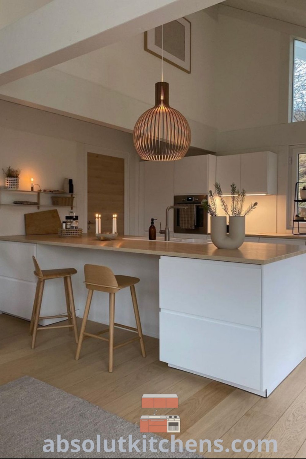 A Nordic interior kitchen showcasing two stools next to a spacious island, emphasizing an open concept design that fosters connection with the living room. This cozy space represents the essence of Nordic home design with unique decor inspirations for elegant and functional kitchen ideas. Learn more at wellnesswink.com.