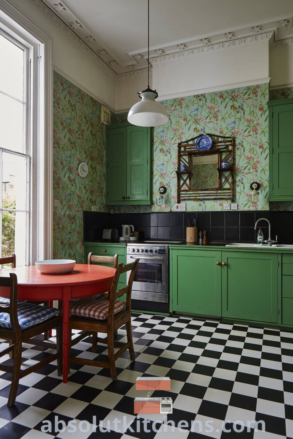 A kitchen featuring green cabinets, black and white checkered flooring, and stylish wallpaper design ideas from absolutkitchens.com. This urban interior design captures an English townhouse aesthetic, providing cozy decor ideas for homes or apartments. Explore unique decorating tips for contemporary kitchens at absolutkitchens.com.
