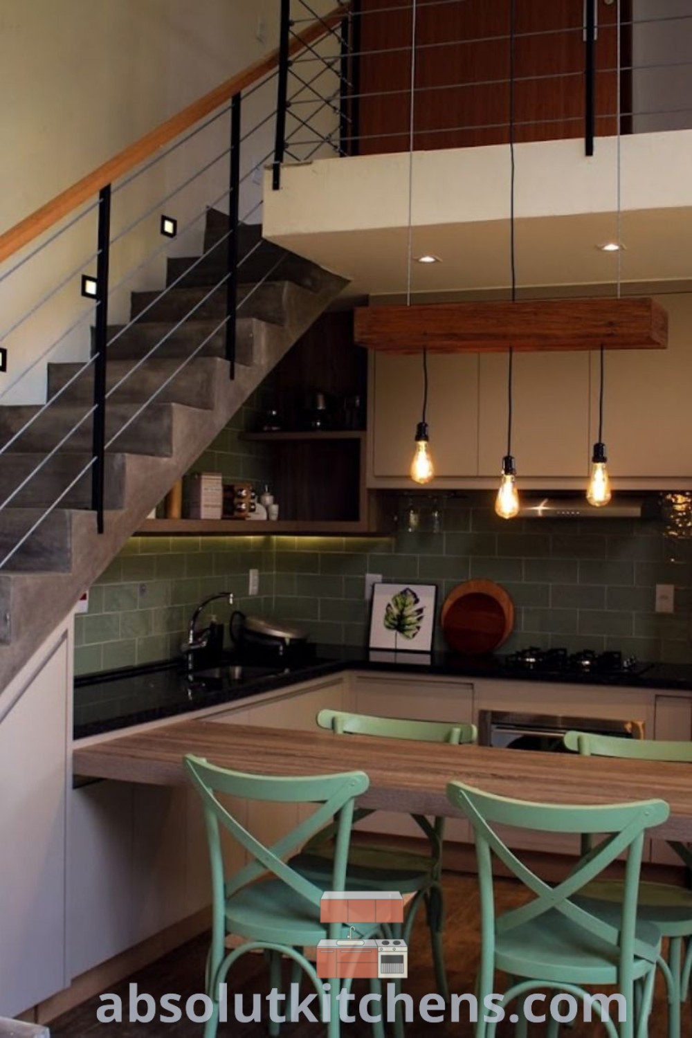 A cozy kitchen and dining area with stairs next to the kitchen leading up to a mezzanine loft. This space creatively utilizes the area under stairs for a small kitchen bar, offering inspiring decor ideas for maximizing functionality in your home. Find more unique ideas at wellnesswink.com.