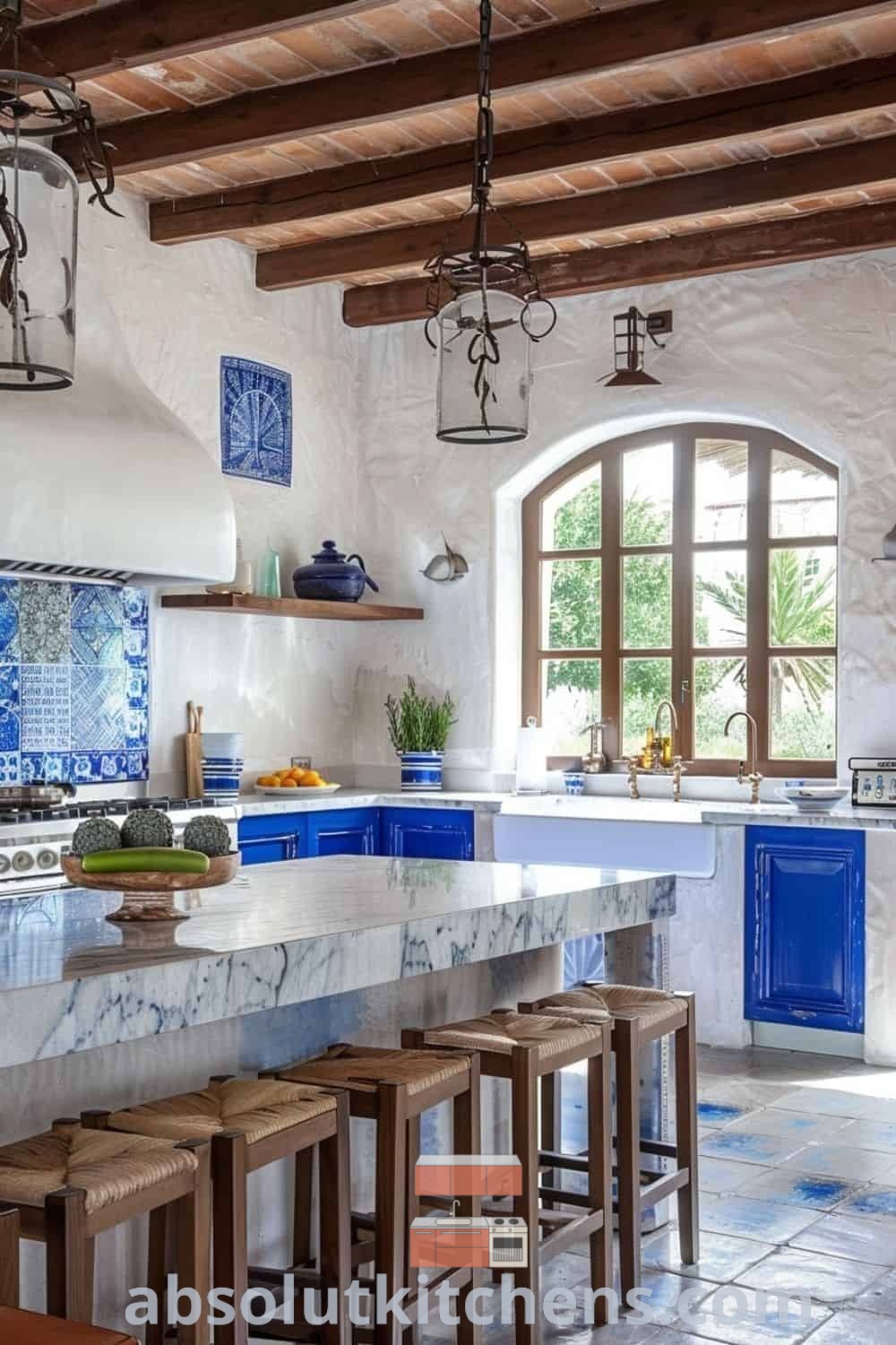 A large luxury farmhouse kitchen with blue and white tiles on the counter tops, wooden stools, and an arched window, showcasing Greek style home aesthetics and elegant Mediterranean kitchen design. Find inspiring ideas for house or apartment decor at absolutkitchens.com.