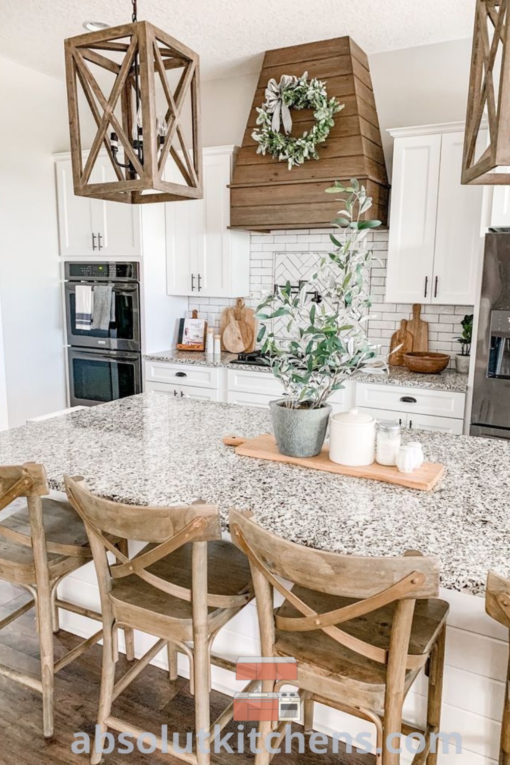 A bright farmhouse kitchen with white cabinets and marble countertops, featuring wooden chairs at the center island. This design represents a modern farmhouse aesthetic, providing cozy and functional decor ideas for houses and apartments. Visit absolutkitchens.com for more inspiring kitchen ideas and design tips.
