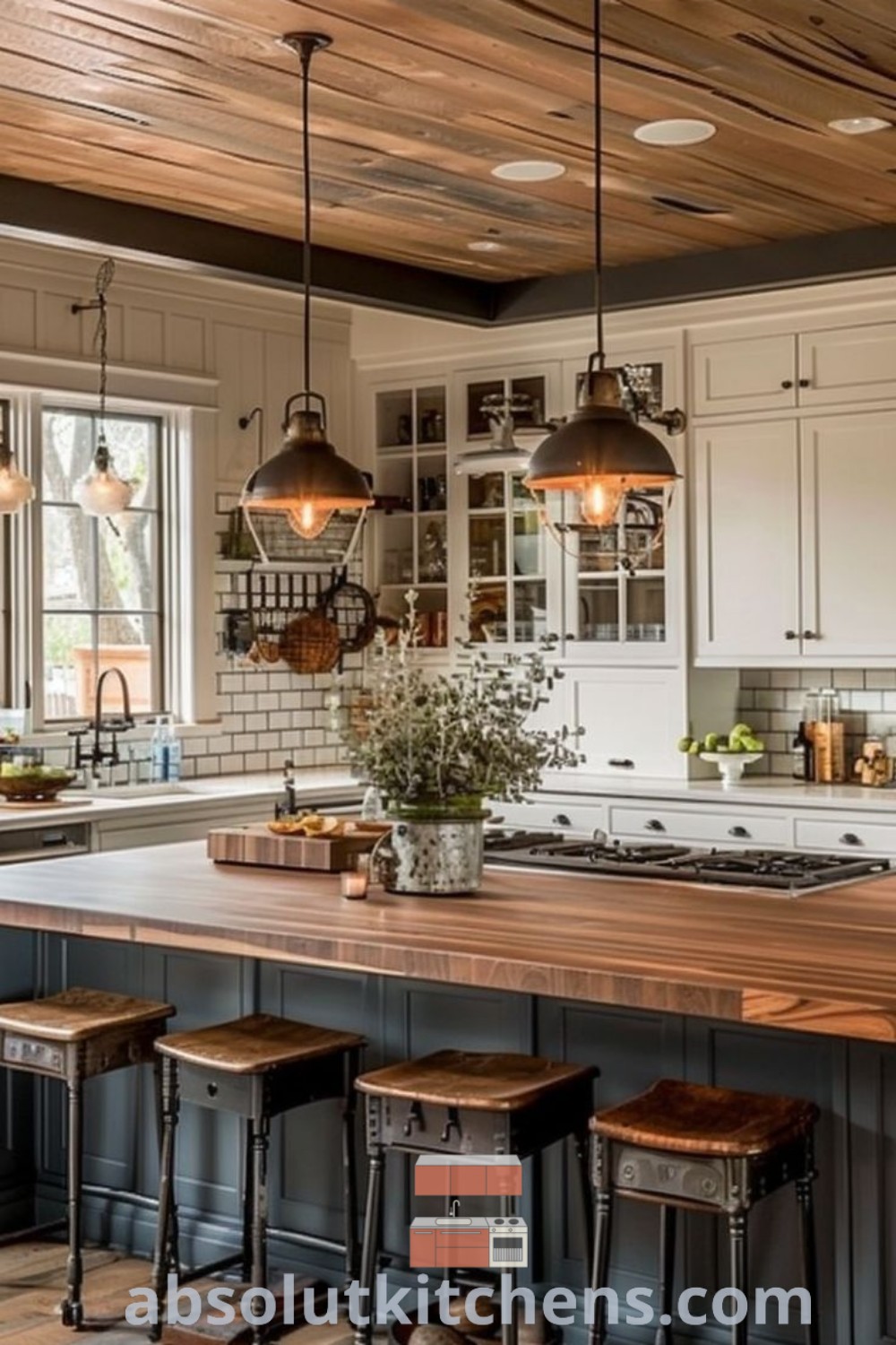 A farmhouse kitchen with an attractive island and stools in front of the wood top, surrounded by wooden flooring, embodying cozy cabin style and functional kitchen design trends. This big island kitchen is perfect for cooking and socializing, offering inspiring ideas for house or apartment decor at absolutkitchens.com.